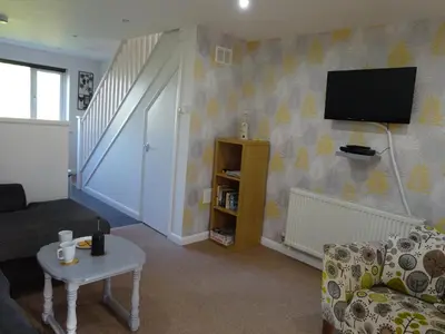 a living room with a couch and a tv on a wall at Newquay Villa 127 in Newquay