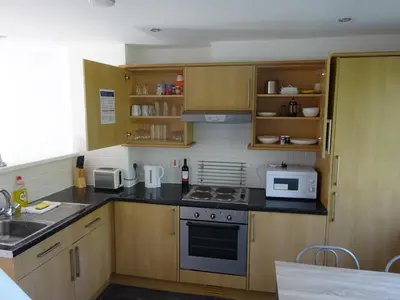 a kitchen with wooden cabinets and a stove top oven at Newquay Villa 127 in Newquay