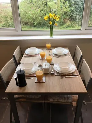 a wooden table with plates and glasses of orange juice at Newquay Villa 127 in Newquay