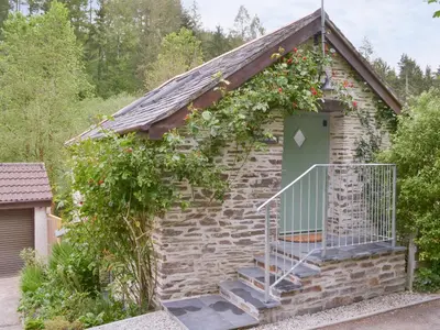 a brick building with a door with a flowering plant on it at Ladyvale Barn in Cardinham