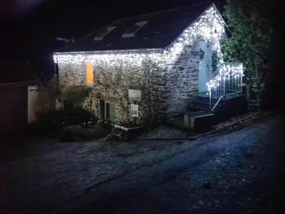 a house with lights on the side of it at night at Ladyvale Barn in Cardinham