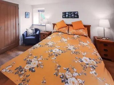 a bed with an orange bedspread with flowers on it at Ladyvale Barn in Cardinham