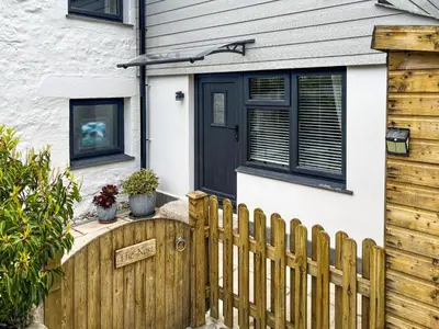a wooden fence in front of a house with a black door at The Nest in Uny Lelant