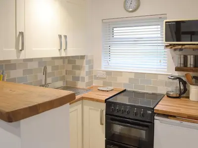 a kitchen with white cabinets and a black stove at The Nest in Uny Lelant