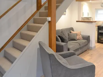 a living room with a couch and stairs at The Nest in Uny Lelant