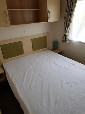 a white bed in a room with a window at Caravan Willerby Rio in Looe