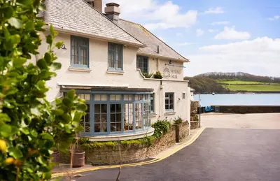 a house with a driveway in front of a body of water at The Rising Sun in Saint Mawes