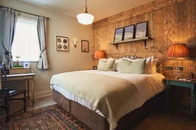 a bedroom with a bed and a wooden wall at The Rising Sun in Saint Mawes