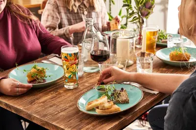 a group of people sitting at a table with plates of food at The Rising Sun in Saint Mawes