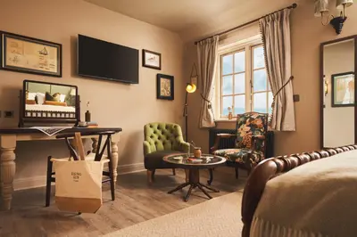 a living room with a bed and a table and a chair at The Rising Sun in Saint Mawes