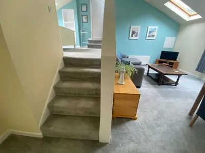 a staircase in a living room with a couch and a table at The Annexe, Tregoose House in Newquay