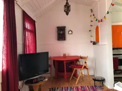 a living room with a red table and a television at Hippy beach shack in Hayle