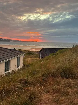 a house on the side of a hill next to the ocean at Hippy beach shack in Hayle