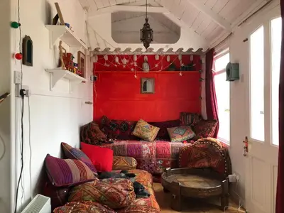 a living room with a couch and a red wall at Hippy beach shack in Hayle