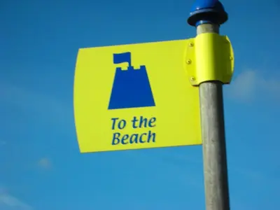a yellow sign on a pole with the words to the beach at Chalet 151, Perran Sands in Perranporth