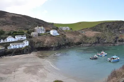 three boats in a body of water with houses at The Gallery in Port Isaac