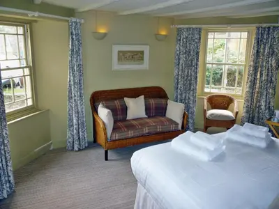 a room with two beds and a couch and windows at Royal Oak Inn in Lostwithiel
