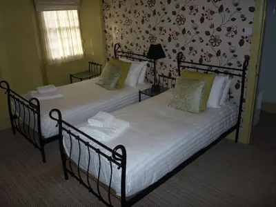 two twin beds in a room with floral wallpaper at Royal Oak Inn in Lostwithiel