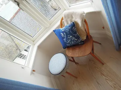 a chair with pillows on it next to a window at Trevose Harbour House in St Ives