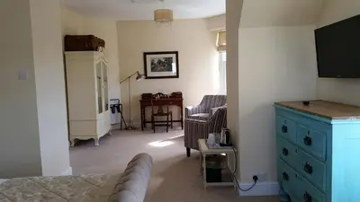a bedroom with a blue dresser and a living room at Pencubitt House in Liskeard