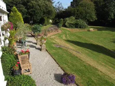 a garden with a bench and flowers in a yard at Pencubitt House in Liskeard