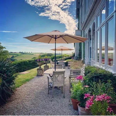 a table and chairs with an umbrella in front of a building at Pencubitt House in Liskeard