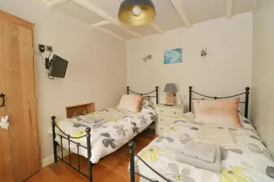 a bedroom with two beds and a tv on the wall at TOWN CENTRE contemporary cottage in Padstow