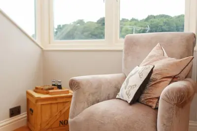 a chair with two pillows sitting next to a window at TOWN CENTRE contemporary cottage in Padstow