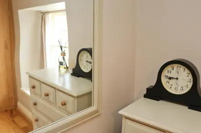 two clocks sitting on a dresser in front of a mirror at TOWN CENTRE contemporary cottage in Padstow
