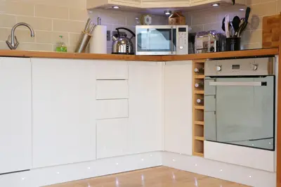 a kitchen with white cabinets and a counter with a microwave at TOWN CENTRE contemporary cottage in Padstow