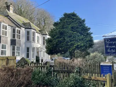 a sign in front of houses and a tree at Penryn House Hotel in Polperro