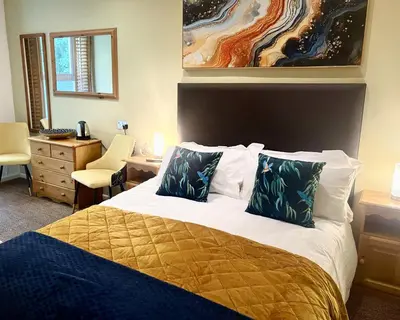 a bedroom with a large bed with two pillows at Penryn House Hotel in Polperro