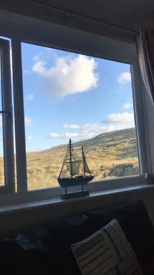 a window with a small boat in a room at Dunes View - Atlantic Bay in Perranporth