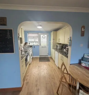 a kitchen with an archway leading into a kitchen with a table at Dunes View - Atlantic Bay in Perranporth