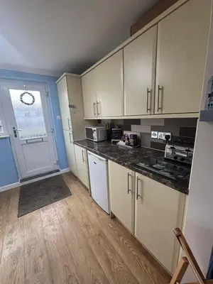 an empty kitchen with white cabinets and a door at Dunes View - Atlantic Bay in Perranporth