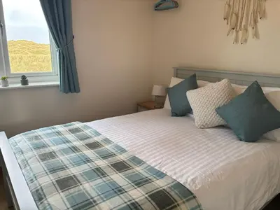 a bedroom with a bed with pillows and a window at Dunes View - Atlantic Bay in Perranporth