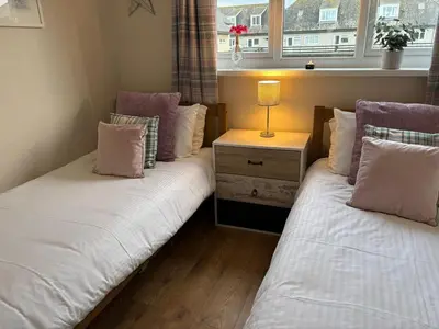 two beds sitting next to a window in a room at Dunes View - Atlantic Bay in Perranporth