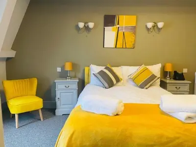 a bedroom with a yellow bed and a yellow chair at The Swan Hotel in Wadebridge