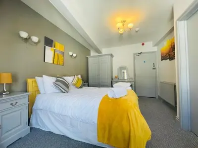 a bedroom with a large bed with a yellow blanket at The Swan Hotel in Wadebridge