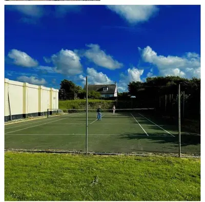 two people playing tennis on a tennis court at Chalet 18 Widemouth Bay Holiday Village in Bude