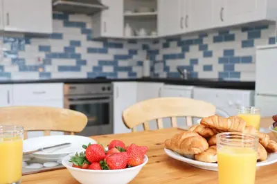 a wooden table with strawberries and croissants and glasses of orange juice at BY THE BEACH Harlyn Bay in St Merryn