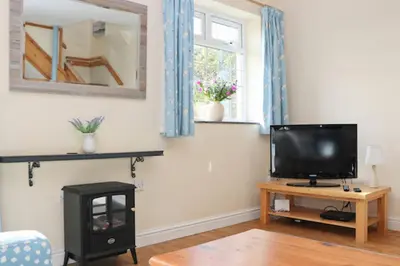 a living room with a tv and a wooden table at BY THE BEACH Harlyn Bay in St Merryn