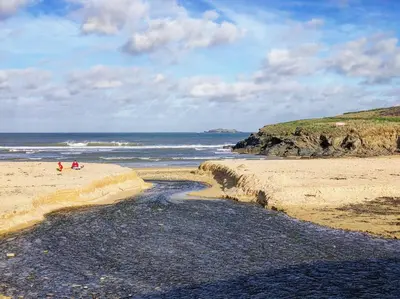 two people sitting on a beach near the ocean at BY THE BEACH Harlyn Bay in St Merryn
