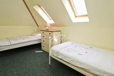 a bedroom with two beds and a dresser and windows at BY THE BEACH Harlyn Bay in St Merryn