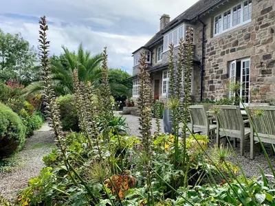 a garden with chairs and flowers in front of a house at Penquite Holiday Accommodation in Uny Lelant