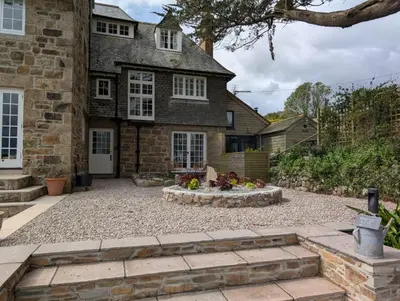 a stone house with a fire pit in the yard at Penquite Holiday Accommodation in Uny Lelant