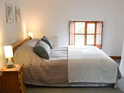 a bedroom with a bed with pillows and a window at Bruce's Cottage in Saint Erth
