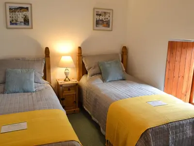 a bedroom with two beds and a lamp on a night stand at Bruce's Cottage in Saint Erth