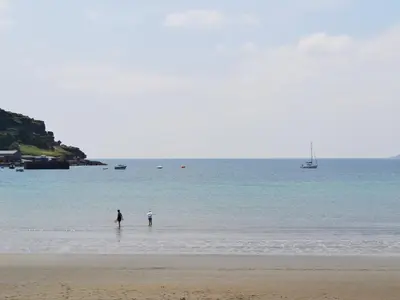 two people standing in the water on a beach at Bruce's Cottage in Saint Erth