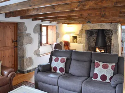 a living room with a couch and a stone fireplace at Bruce's Cottage in Saint Erth